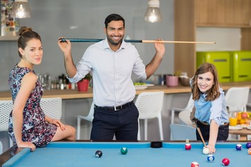 Wall Mural - Smiling business colleagues playing pool in office space