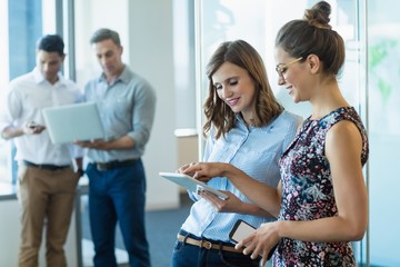 Wall Mural - Smiling business colleagues using digital tablet