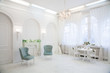 Classical white interior room with turquoise chairs, vintage style chandelier, fireplace, big window and spring flowers in vase on table. Horizontal