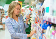 Young woman is choosing toothbrush in supermarket.
