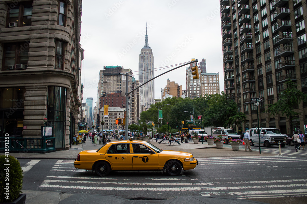 Cab and Empire State Building under a Grey Sky in Manhattan, New York, USA - obrazy, fototapety, plakaty 