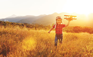 Child pilot aviator with airplane dreams of traveling in summer  at sunset.