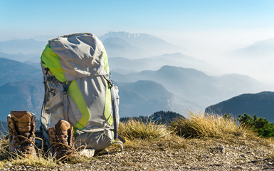 Hiking equipment. Backpack and boots on top of mountain.