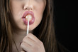 Juicy big lips of a young woman suck a lollipop, nice long fingers with red nail polish,isolated black background