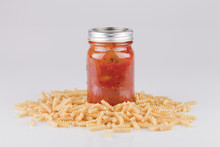 Jar Of Spaghetti Sauce With Dry Pasta On A White Surface. Canned Sauce With Fusili Isolated On White Background.