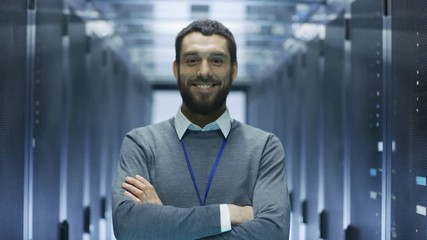 Wall Mural - IT Engineer Walks Into Camera Focus, Smiles  and Folds His Arms on a Chest. He's Working in Data Center Full of Rack Servers.Shot on RED EPIC-W 8K Helium Cinema Camera.
