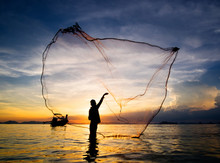 Hunting For Sunset. Silhouette Of Fisherman Throwing Fishing Net Into The Sea, Thailand.