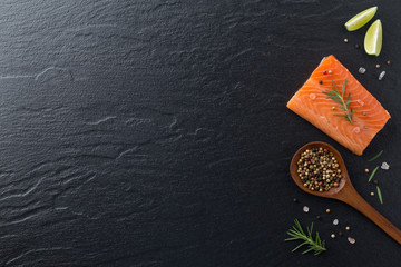 Beautiful composition of fresh salmon fillet with rosemary, salt, lemon and peppercorn on dark background. Good for space and background