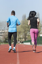 Young Couple Exercise Running On The Track