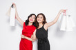 Two happy attractive young women with shopping bags on white background