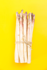 Wall Mural - White asparagus bundle, on vivid yellow background