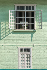 Wall Mural - Antique white frame wooden window with light and shadow the old green brick wall retro style