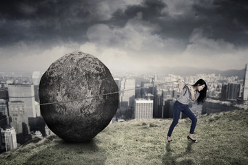 Wall Mural - Female entrepreneur with big stone on the hill