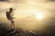 © Creativa Images - Female hiker using binocular in the cliff