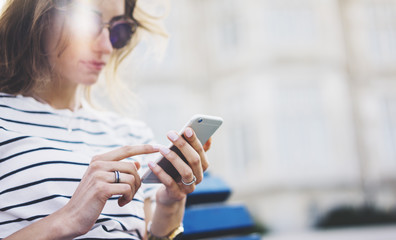 Hipster texting message on smartphone or technology, mockup of blank screen. Girl using cellphone on building castle background close. Tourist female hands holding gadget on blurred summer backdrop