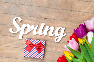  photo of beautiful bunch of colorful tulips, tablet and cute gift on the wonderful brown wooden background