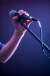 © puhimec - hand with microphone on a black background, the music concept, beautiful lighting on the stage