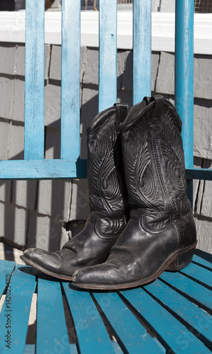 Close Up Of A Pair Of Black Leather Cowboy Boots On A Blue Rocking