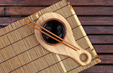 Wall Mural - Bamboo mat, soy sauce, chopsticks on dark wooden table. Top view with copy space