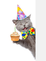 Poster - Happy cat in birthday hat with cupcake holding a pointing stick and points on empty banner. isolated on white background