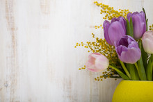 Bouquet Of Tulips In A Yellow Vase On A Wooden Background.