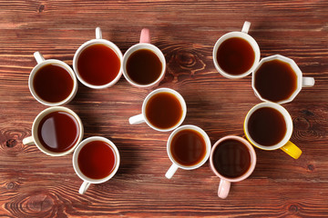 Poster - Delicious tea in cups forming spiral on wooden background