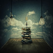 © psychoshadow - Idea concept with a boy standing on a pile of books trying to switch on the light bulbs, surrounded by concrete walls with clouds texture as thinking limitations. In search of knowledge.