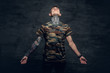 © Fxquadro - A man with tattoos on his neck, face and arms, dressed in a camouflage t shirt.