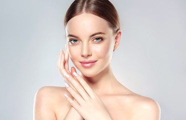 beautiful young woman with clean fresh skin touch own face . facial treatment . cosmetology , beauty