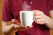 © OB production - The man in the red shirt shows a clean white Cup. Cup for your design. Empty mug