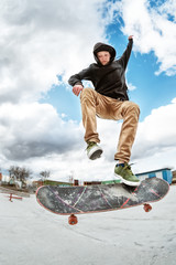 A young skateboarder makes Wallie in a skatepark, jumping on a skateboard into the air with a coup