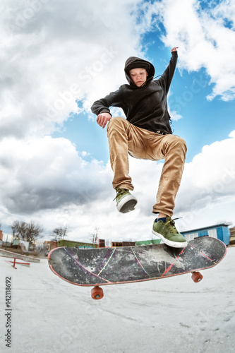 Tela A young skateboarder makes Wallie in a skatepark, jumping on a skateboard into t