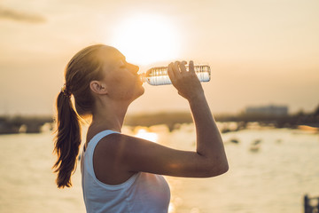 Sporty woman drinking water outdoor on sunny day