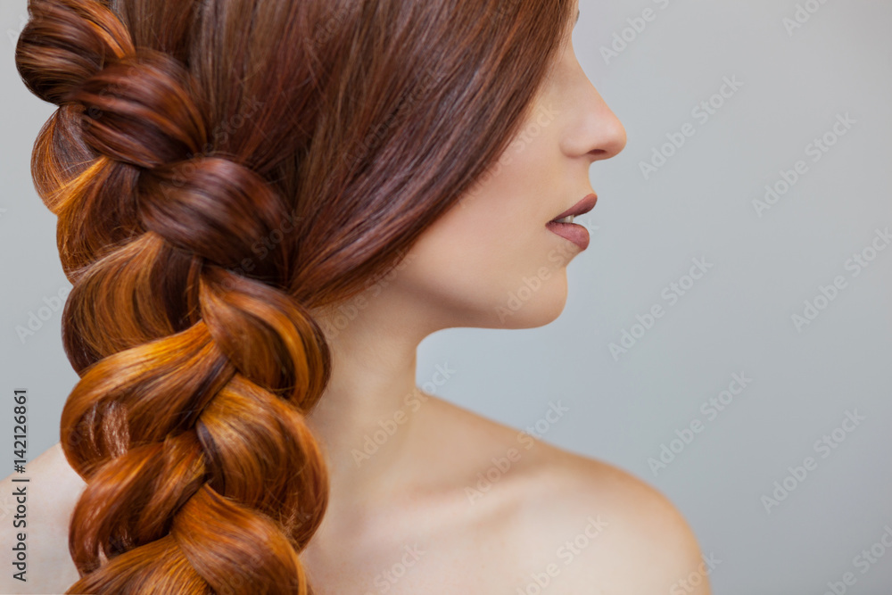 Beautiful girl with long red hair, braided with a French braid, in a beauty salon. Professional hair care and creating hairstyles. - obrazy, fototapety, plakaty 