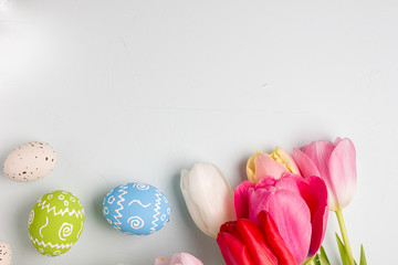 Painted easter eggs and bouquet of spring tulips closeup on a light blue background with space for congratulation