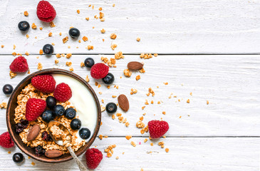 Wall Mural - bowl of oat granola with yogurt, fresh raspberries, blueberries and nuts