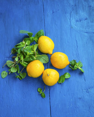 Wall Mural - Fresh lemons and mint leaves on wooden background