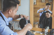© Odua Images - barber making haircut of attractive man in barbershop