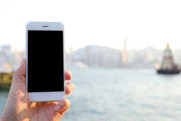 Poster - Hand holding smartphone with habour and skyline background