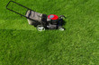 Lawn mower in the garden on green grass photographed from above