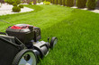 Lawn mower in the garden on green grass