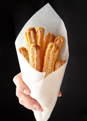 Wall Mural - churros traditional spain or mexican street fast food baked sweet dough snack in hand cone of parchm