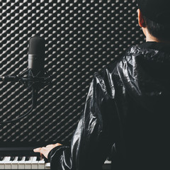 Sticker - back of male asian musician playing piano with microphone in recording studio