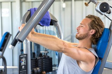 Wall Mural - Man doing chest exercises on vertical bench press machine.