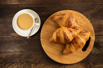 Wall Mural - Three crunchy croissants and coffe on wooden board 