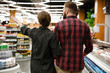 © Drobot Dean - Back view of young loving couple in supermarket choosing products.