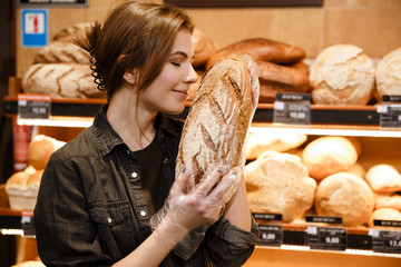 Young happy woman in supermarket choosing pastries.