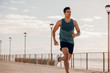 © Jacob Lund - Fit young man running on seaside promenade