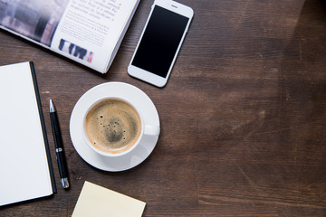 Poster - Top view of coffee cup, smartphone with blank screen, notebook with pen and newspaper on wooden table