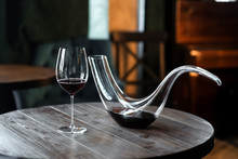 Decanter With Red Wine And Glass On Wooden Table In Interior. Free Space For Text. Still Life